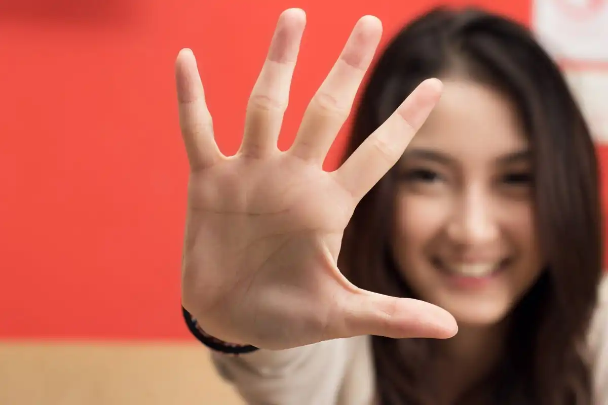 woman holding up hand with 5 fingers